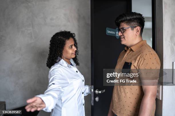 doctor opening door and greeting patient - entering hospital stock pictures, royalty-free photos & images