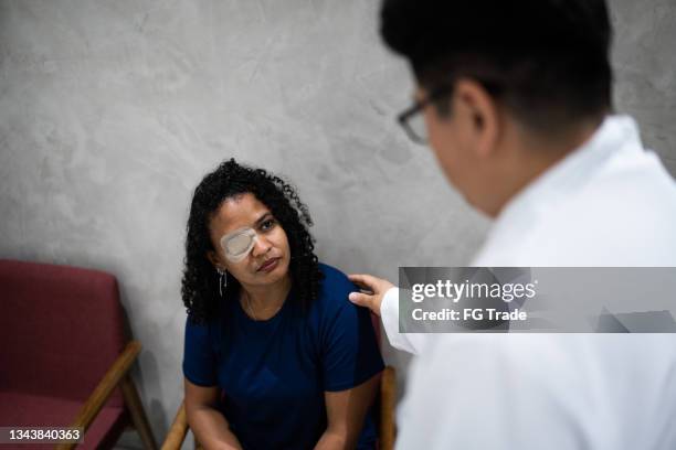 doctor talking to patient in medical clinic waiting room - one eyed stock pictures, royalty-free photos & images
