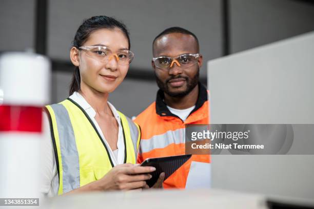 diversity of production engineers posing towards the camera while standing inside of a circuit power supply cabinet of laser cutting machine in the manufacturing industry. - live stage stockfoto's en -beelden