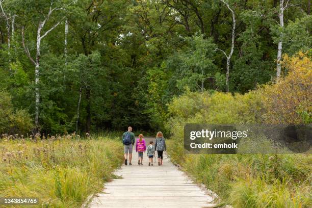 family enjoying walk through woods in early autumn - minnesota forest stock pictures, royalty-free photos & images