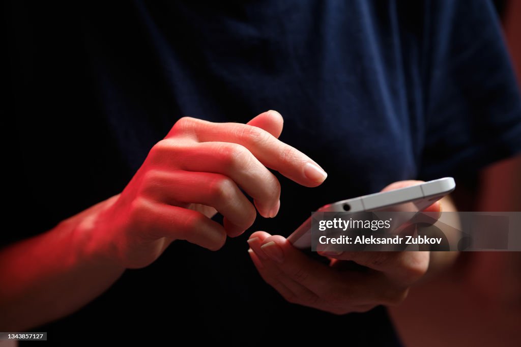 A mobile phone in the hands of a girl. A young woman in a black T-shirt is holding a phone. The fraudster sends an email message. The work of a freelancer, businessman. The wife checks messages and notifications on social networks. Wireless technologies.