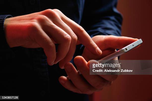 a mobile phone in the hands of a man. a young guy in a black t-shirt is holding a phone. the fraudster sends an email message. i work as a freelancer, businessman. the husband checks messages and notifications on social networks. wireless technologies. - mensaje de móvil fotografías e imágenes de stock
