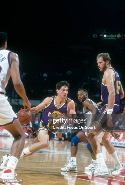 John Stockton of the Utah Jazz drives towards the basket past Michael Adams of the Washington Bullets during an NBA basketball game circa 1991 at the...