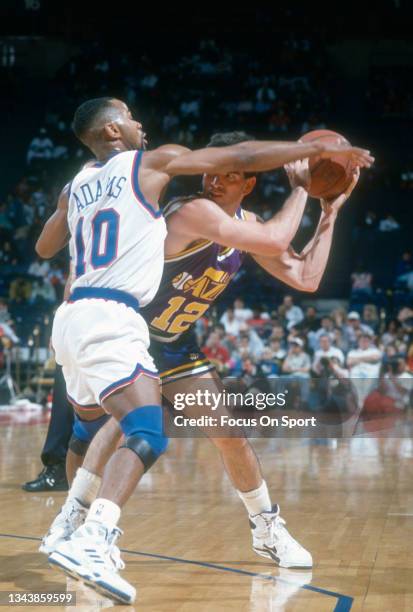 John Stockton of the Utah Jazz looks to pass over the top of Michael Adams of the Washington Bullets during an NBA basketball game circa 1991 at the...