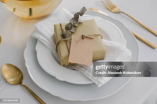 holiday gift present with empty tag on white plate on table. - christmas tag stockfoto's en -beelden