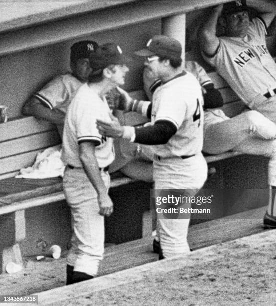 Yankees' manager Billy Martin comes up off the dugout bench to confront right fielder Reggie Jackson who is coming into the dugout after being lifted...