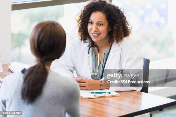 mid adult female doctor listens attentively to unrecognizable female patient - vrouwenkwesties stockfoto's en -beelden