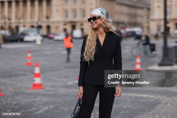 Rose Bertram wearing a black blazer and pants, a black dior bag outside Dior on September 28, 2021 in Paris, France.