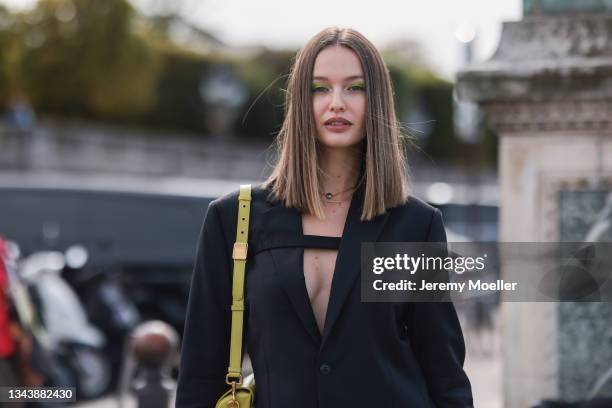 Kristina Romanova wearing a black blazer, black shirts and a yellow bag outside Dior on September 28, 2021 in Paris, France.