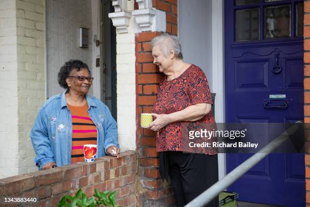 two old friends and neighbours having a chat outside their houses. - neighbour stock pictures, royalty-free photos & images