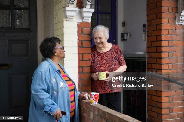 two old friends and neighbours having a chat outside their houses. - buren stockfoto's en -beelden