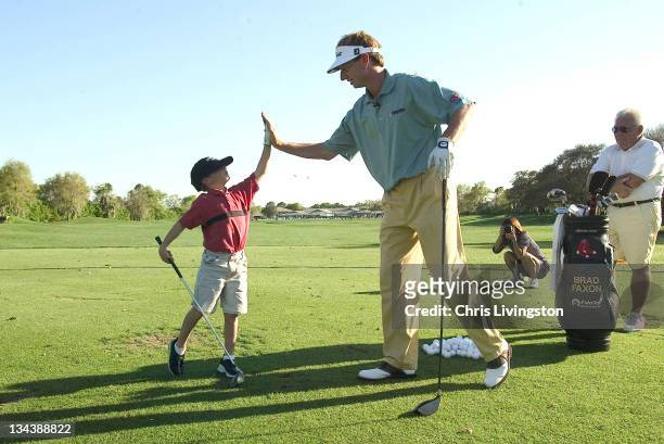 Brice Schiano high-fives golfer Brad Faxon, right, during a kids golf clinic at Bayhill Country Club in Orlando, Florida on Wednesday, 17 March 2004.