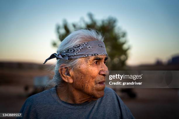 senior navajo native american man portrait while in his back yard at monument valley utah or arizona smiling at the camera on a sunny late afternoon - cherokee indian women stockfoto's en -beelden