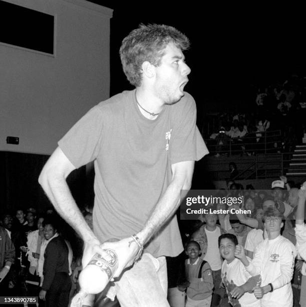 American rapper, bass player and filmmaker Adam Yauch, aka MCA, of the American hip hop group The Beastie Boys, throws beer on the crowd during a...