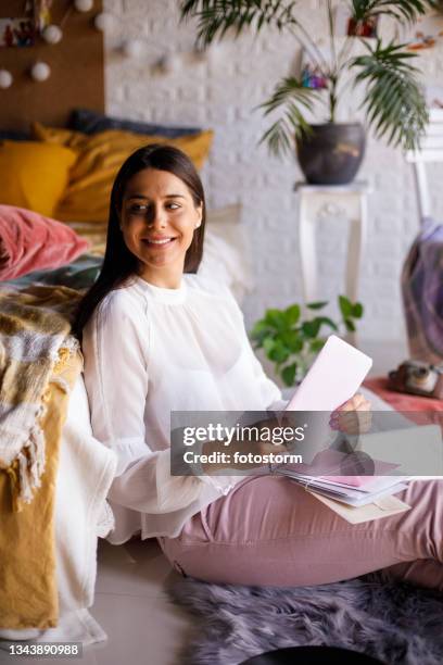 young woman contemplating while opening a love letter - receiving card stock pictures, royalty-free photos & images