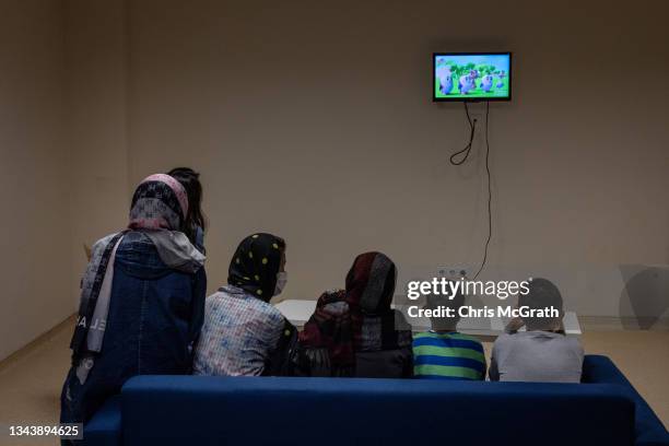 Refugees and migrants are seen watching television at the Kurubas migrant repatriation center during a press tour on September 28, 2021 in Van,...