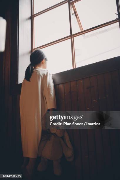 a kid looking outside through window - looking through a doll house stock-fotos und bilder