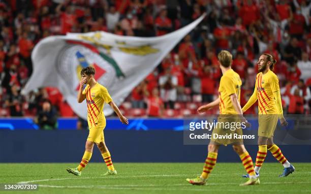 Gavi, Frenkie de Jong and Oscar Mingueza walk off the field dejected after the UEFA Champions League group E match between SL Benfica and FC...