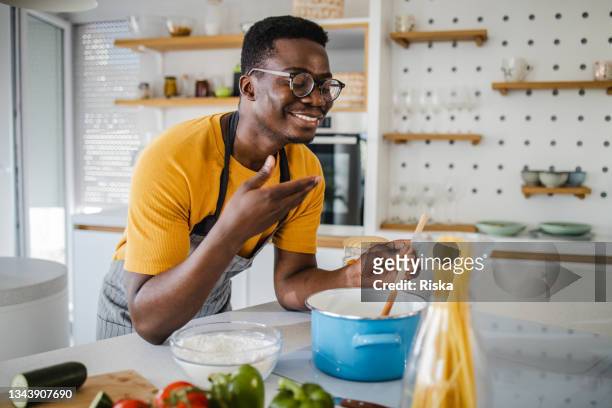 young man at home, preparing a delicious dinner - smelling food imagens e fotografias de stock