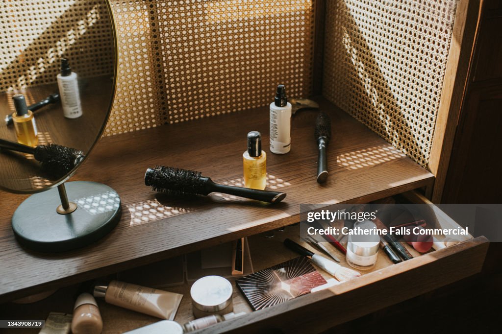 A wooden dressing table in sun with various beauty products
