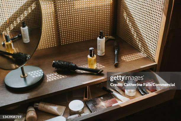 a wooden dressing table in sun with various beauty products - make up bag fotografías e imágenes de stock
