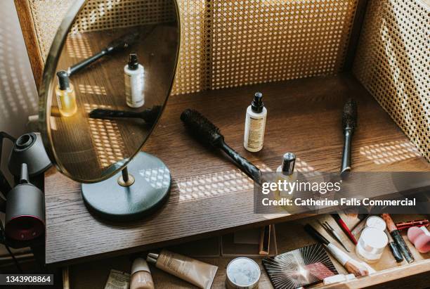 a wooden dressing table in sun with various beauty products, including a hairdryer and diffuser - beauty products stock pictures, royalty-free photos & images