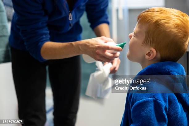 mère nettoyant et vidant le nez de son fils avec un spray nasal salin - solution saline photos et images de collection
