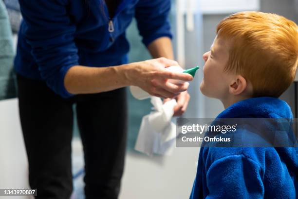 mother cleaning and emptying her son's nose with saline nasal spray - infuus met een fysiologische zoutoplossing stockfoto's en -beelden
