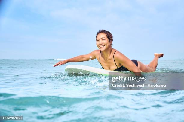 local mother paddling the ocean on surfboard - older woman wet hair stock pictures, royalty-free photos & images