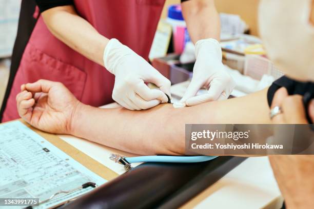 female nurse collects blood from senior patient for testing at hospital - bluttest stock-fotos und bilder