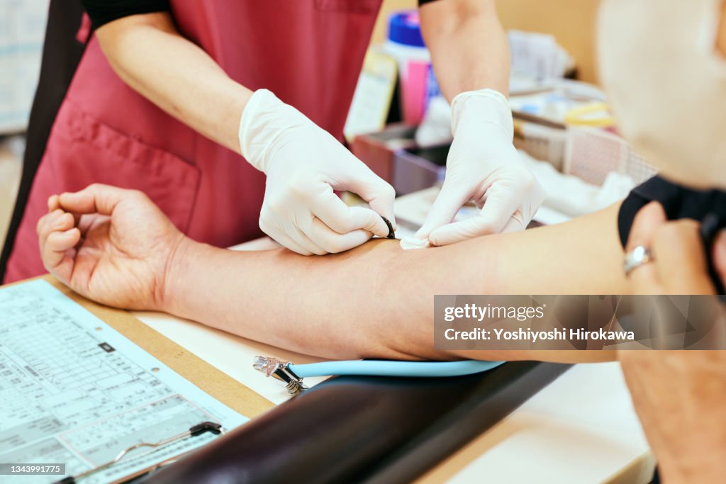 Female nurse collects blood from senior patient for testing at hospital