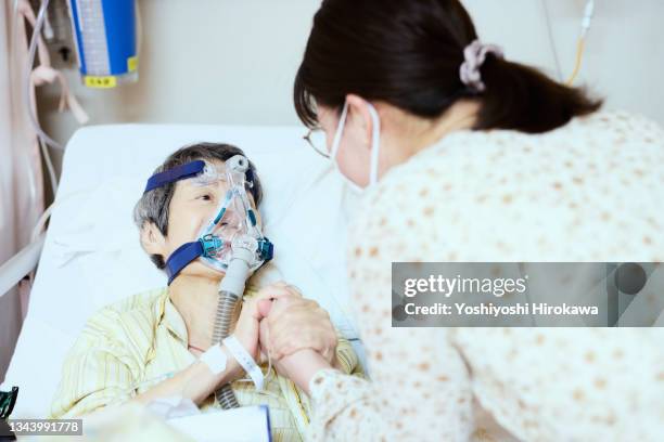 family encouraging mother with oxygen inhaler - hospital ventilator ストックフォトと画像