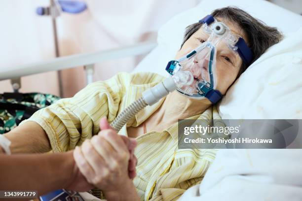 family encouraging mother with oxygen inhaler - elderly care japanese photos et images de collection