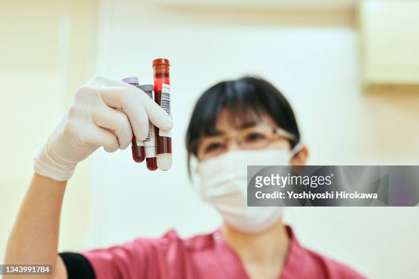 female nurse collects blood from patient for testing at hospital - sangue umano foto e immagini stock