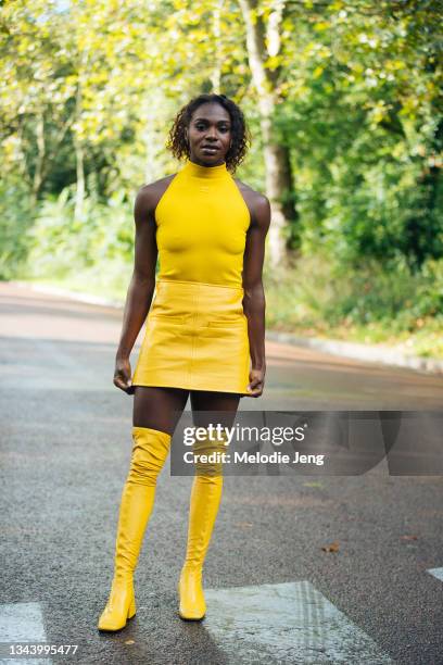 Guest wears a Courreges yellow sleeveless top, yellow leather skirt, and thigh-high leather boots at the Courreges show on September 29, 2021 in...