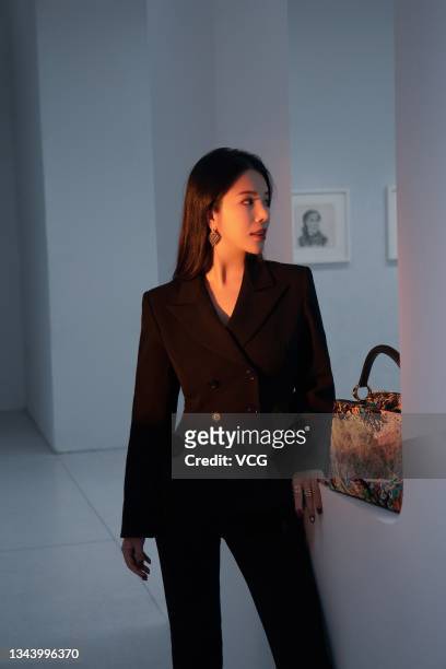 Wendy Yu, founder and president of Yu Holdings, poses with a limited-edition Artycapucines handbag during a photocall for Louis Vuitton at UCCA Edge...
