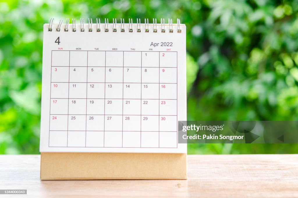 April month, Calendar desk 2022 for organizer to planning and reminder on wooden table with green nature background.