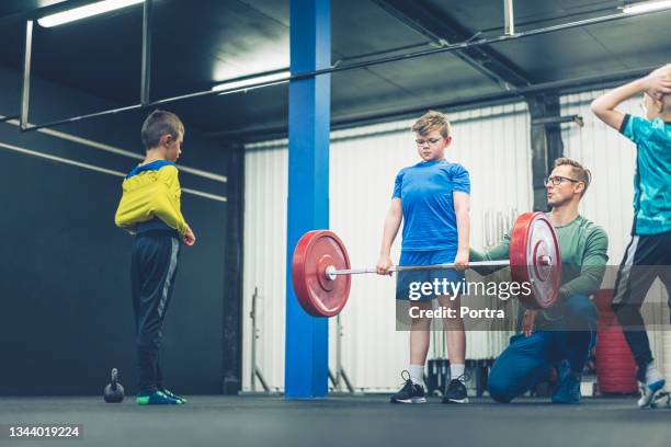 pre-adolescent boy lifting barbell with coach - youth weight training stock pictures, royalty-free photos & images