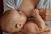 Little baby holding to his mother while breastfeeding