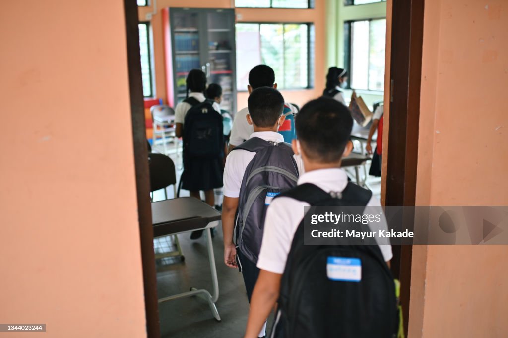 Rear view of School children with schoolbags entering the classroom