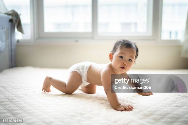 asian baby wearing diaper positive emotion try to crawling on the cozy bed with mother encourage in front  domestic life - baby diaper stockfoto's en -beelden