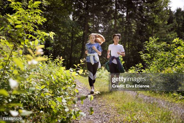 teenage boy and girl jogging down a footpath through the black forest in summertime on a sunny day. - schwarzwald tracht stockfoto's en -beelden