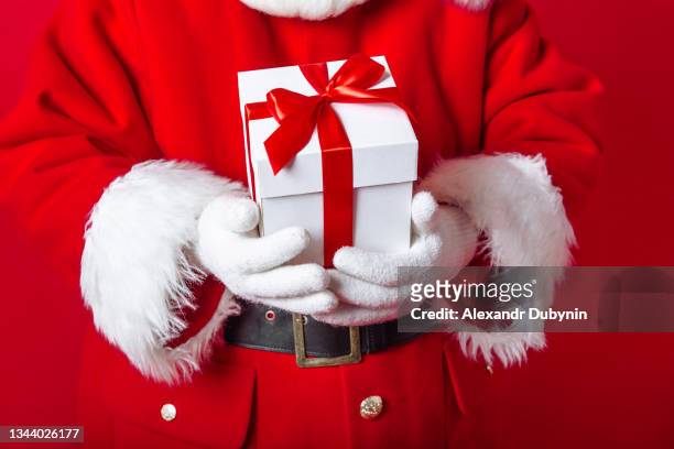 close-up of santa claus hand giving white gift on red background - santa giving out presents stock pictures, royalty-free photos & images