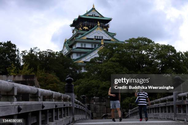 Tourists wearing protective face masks walk through the bridge during the final day of fourth coronavirus state of emergency at Osaka Castle site,...