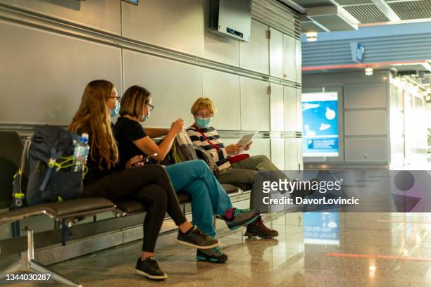 travelers, woman sitting and having conversation while waiting for plane at airport - airport frustration stock pictures, royalty-free photos & images