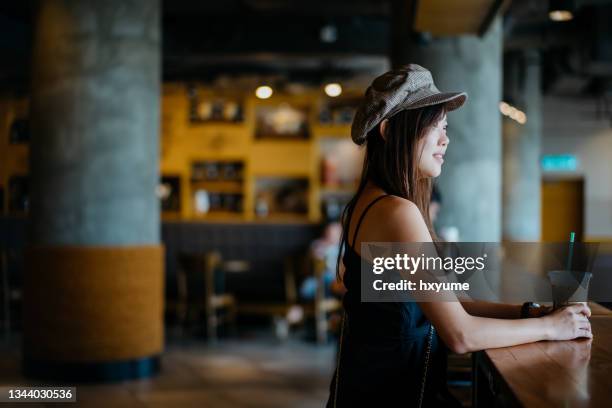 young asian woman enjoying an iced latte in a cafe - cafe culture stock pictures, royalty-free photos & images