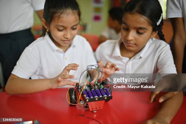school girls making wiring connections in a  robot model car in school - remote controlled car stockfoto's en -beelden