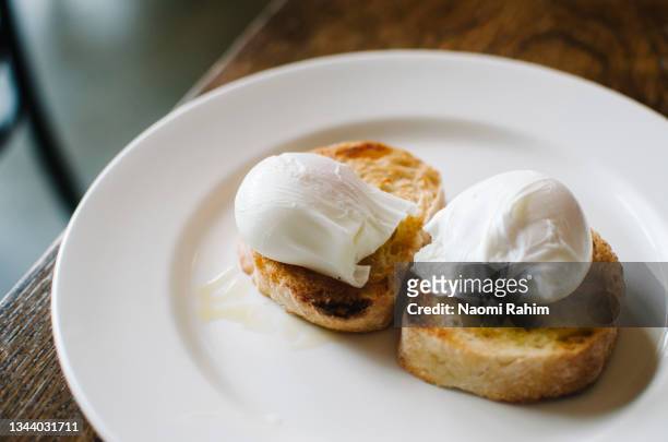 two poached eggs on toast, served on a white plate for breakfast - escalfado fotografías e imágenes de stock
