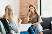 Hopeless teen girl listens to advice from unrecognizable female therapist