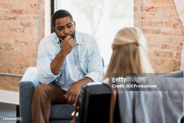 exhausted mid adult man listens to unrecognizable female therapist - psychotherapy stock pictures, royalty-free photos & images